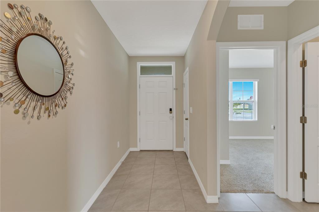 A tiled entryway features a sunburst mirror on the wall and a white front door — 452 NOBLE AVENUE, DAVENPORT, FL