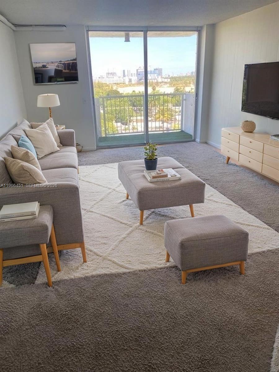 A living room features a grey sofa, matching ottomans, a white rug, and a balcony view — 2020 NE 135th St # 901, North Miami FL 33181, NORTH MIAMI, FL