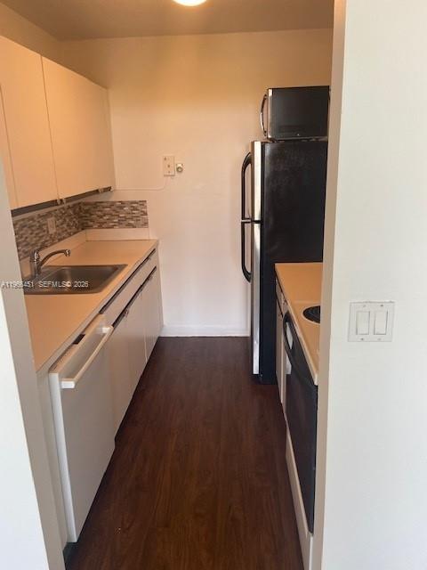 A galley kitchen features white cabinets, a stainless steel refrigerator, and dark wood-look flooring — 2020 NE 135th St # 901, North Miami FL 33181, NORTH MIAMI, FL