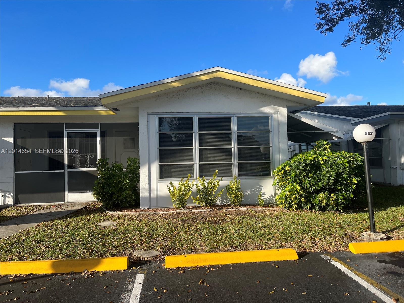The exterior of a single-story home features a screened porch, large windows, and yellow trim — 8621 NW 12th St # D178, Plantation FL 33322, PLANTATION, FL