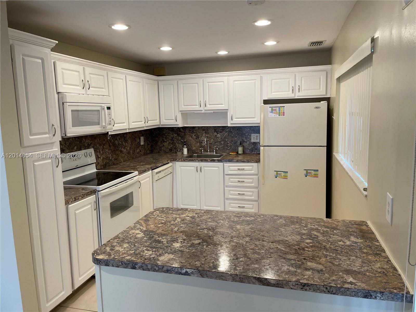 A kitchen features white cabinets, dark patterned countertops, and white appliances — 8621 NW 12th St # D178, Plantation FL 33322, PLANTATION, FL