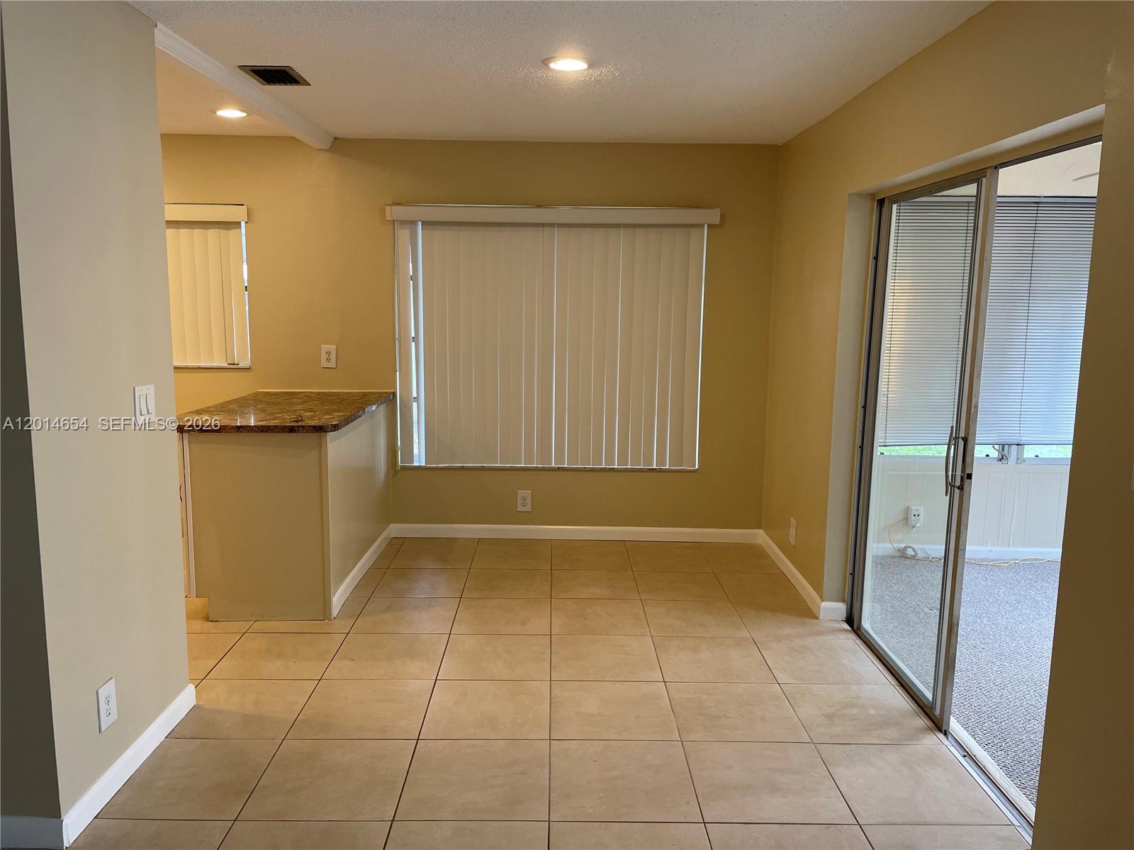 A dining area features tan tile flooring, a breakfast bar, and sliding glass doors — 8621 NW 12th St # D178, Plantation FL 33322, PLANTATION, FL