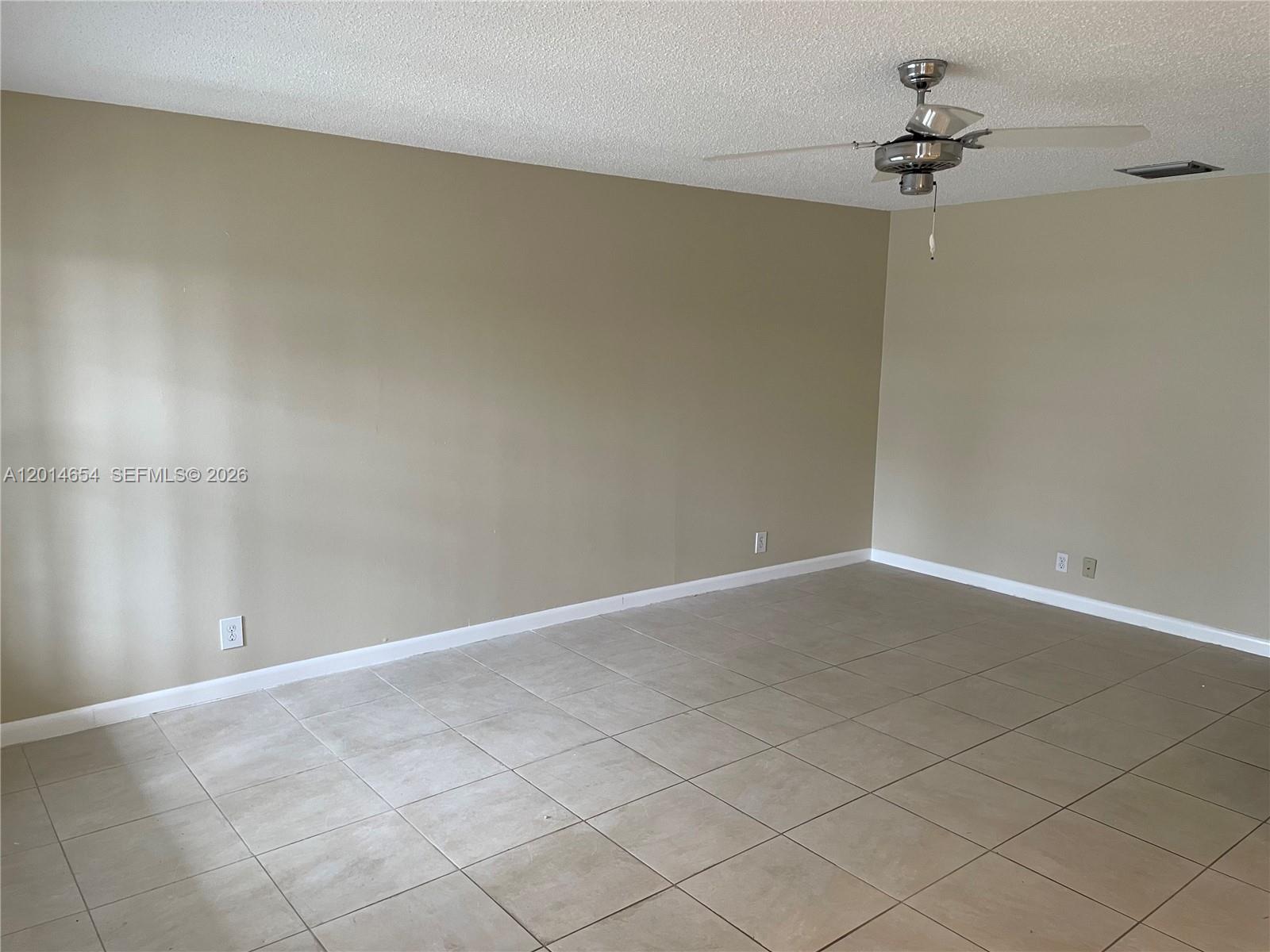 An empty room features beige walls, light-colored tile flooring, and a ceiling fan — 8621 NW 12th St # D178, Plantation FL 33322, PLANTATION, FL