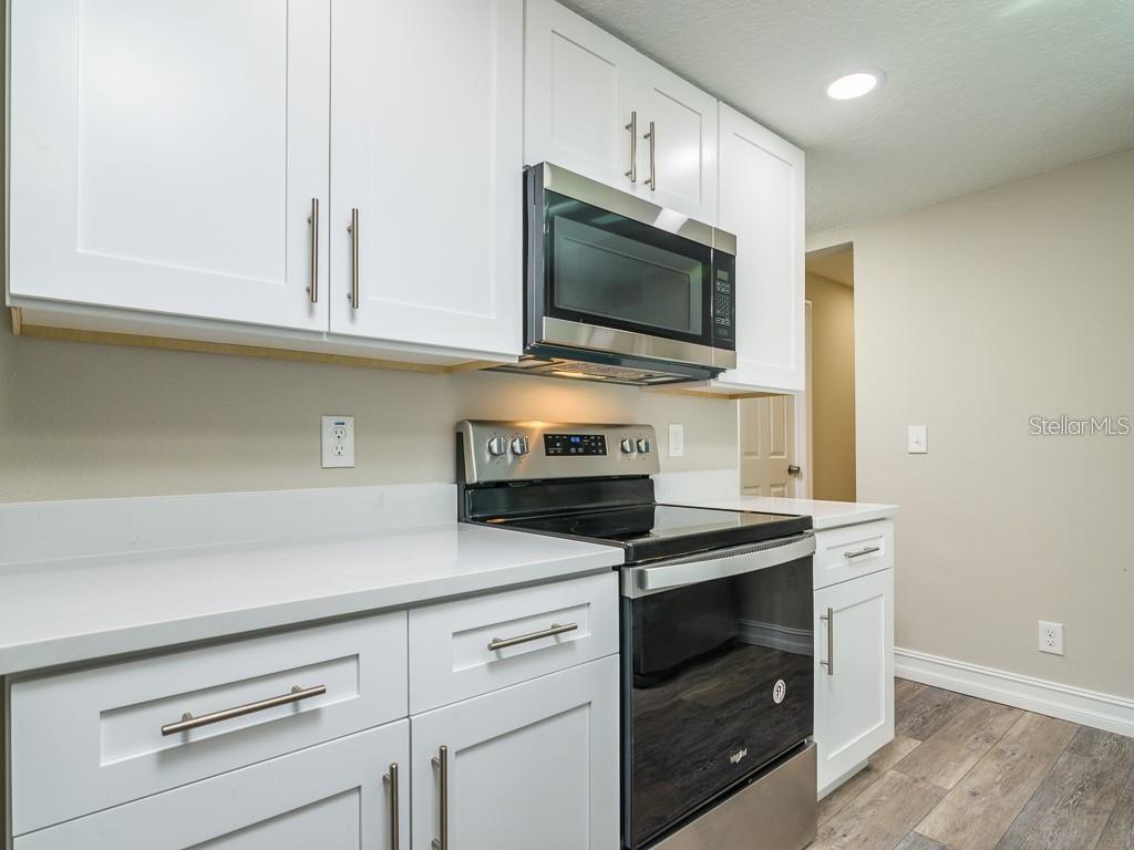 A kitchen featuring white cabinets, stainless steel appliances, and light-colored countertops — 7225 33RD STREET N, ST PETERSBURG, FL