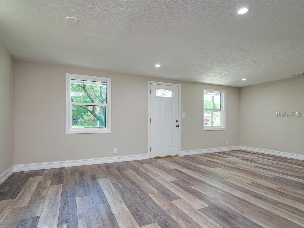 An empty room features light gray walls, wood-look vinyl flooring, two windows, and a white door — 7225 33RD STREET N, ST PETERSBURG, FL