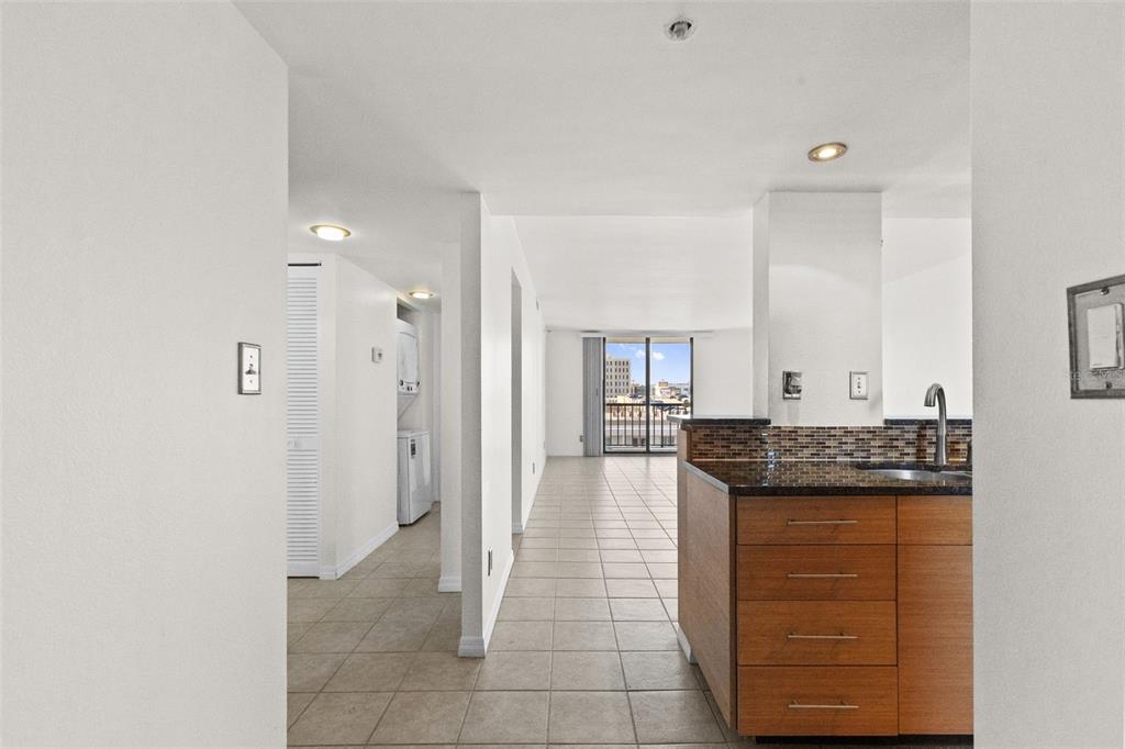 A kitchen island with wood cabinets and granite countertops overlooks a tiled hallway and balcony — 201 W LAUREL STREET UNIT 907, TAMPA, FL