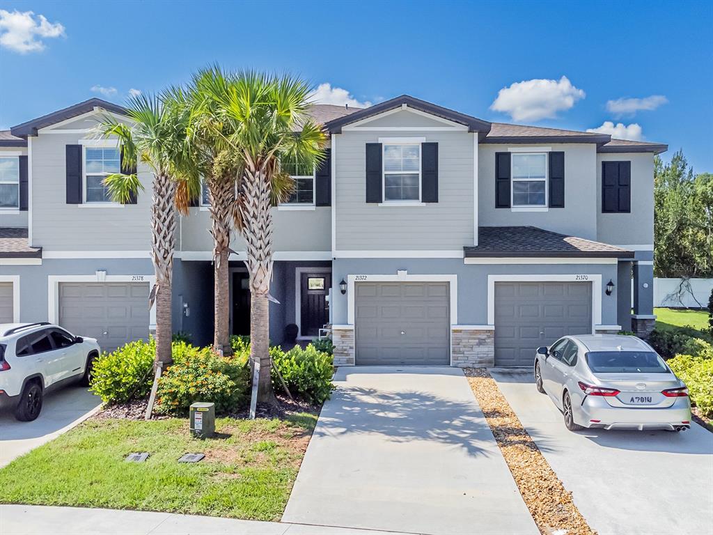 A gated entrance with a sign reading The Townes at Lake Thomas under a blue sky — 21372 DARTER ROAD, LAND O LAKES, FL