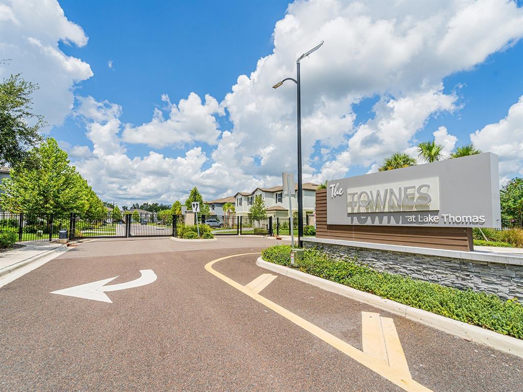 The rear exterior of a two-story townhouse features a screened-in patio and small trees — 21372 DARTER ROAD, LAND O LAKES, FL