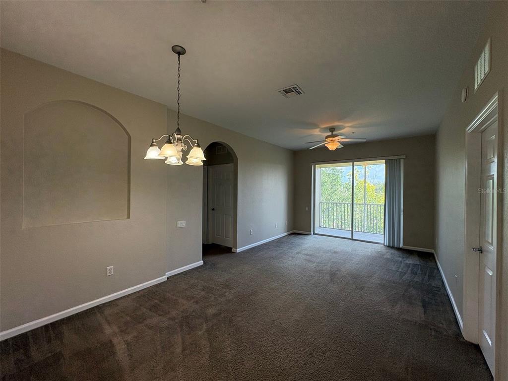A carpeted living and dining area features a chandelier, ceiling fan, and sliding glass doors — 3314 ROBERT TRENT JONES DRIVE UNIT 406, ORLANDO, FL