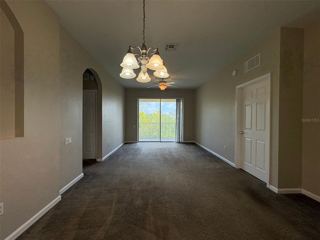 A carpeted living room features a chandelier, a ceiling fan, and a sliding glass door — 3314 ROBERT TRENT JONES DRIVE UNIT 406, ORLANDO, FL