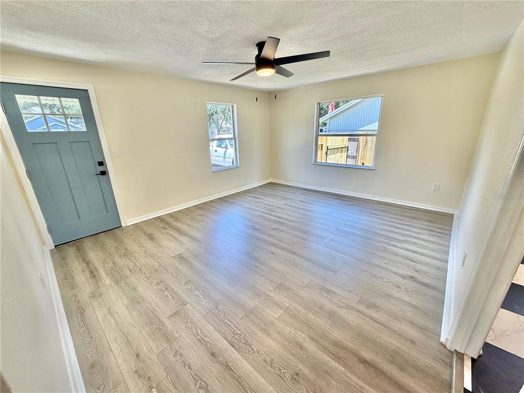 An empty room with light wood-look flooring, a ceiling fan, and a blue front door — 3530 51ST AVENUE N, ST PETERSBURG, FL