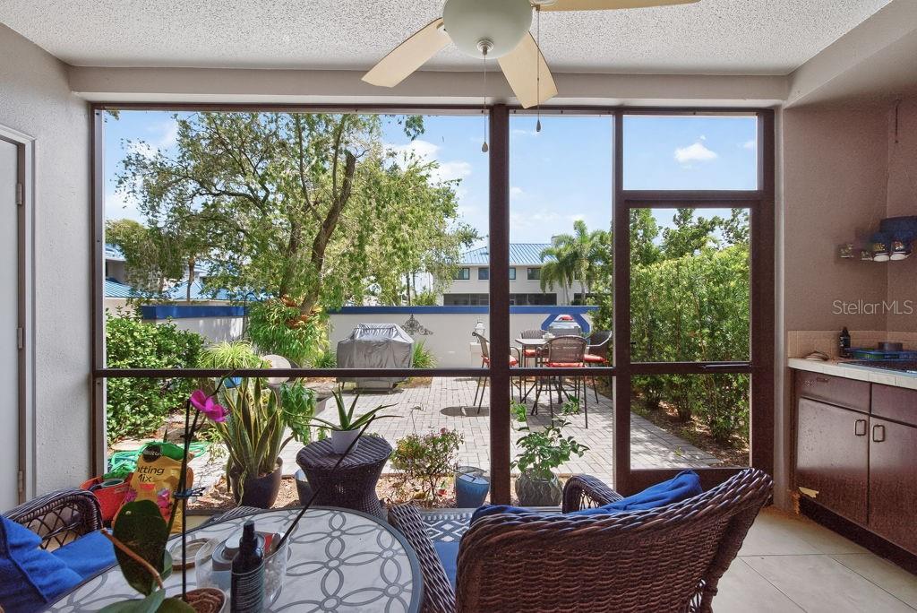 A sunroom with wicker furniture overlooks a paved patio through large screened windows — 1672 WATERMARK CIRCLE NE, ST PETERSBURG, FL