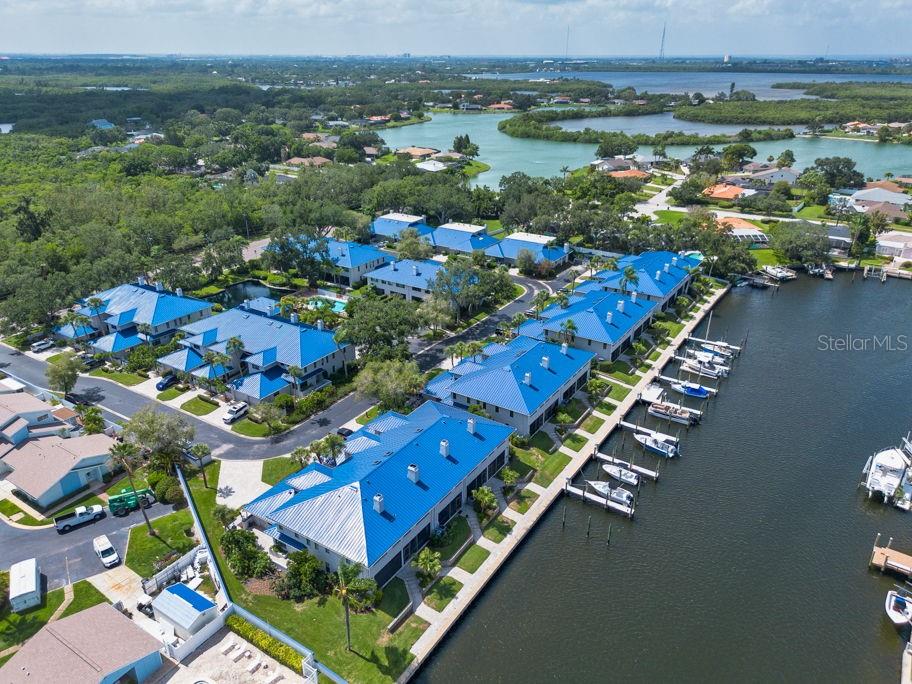 An aerial view of waterfront townhomes with blue metal roofs and a private boat dock — 1672 WATERMARK CIRCLE NE, ST PETERSBURG, FL