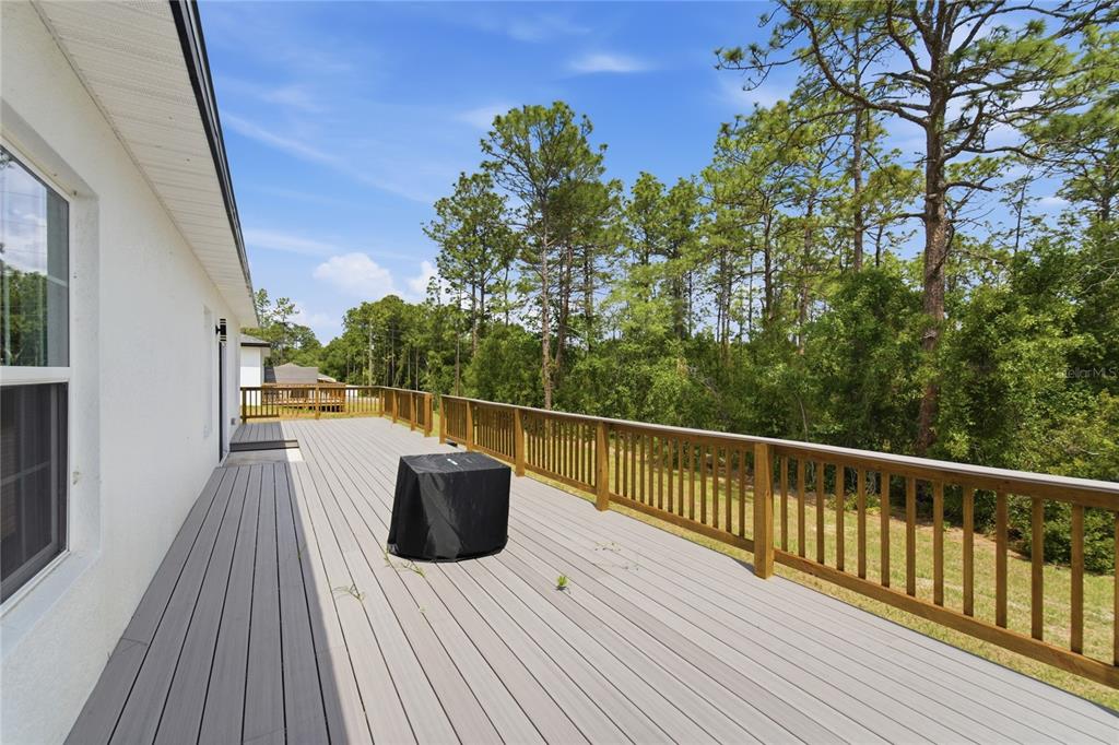 A spacious elevated deck with gray composite flooring and a wooden railing overlooks wooded land — 785 MARION OAKS TRL UNIT 785, OCALA, FL