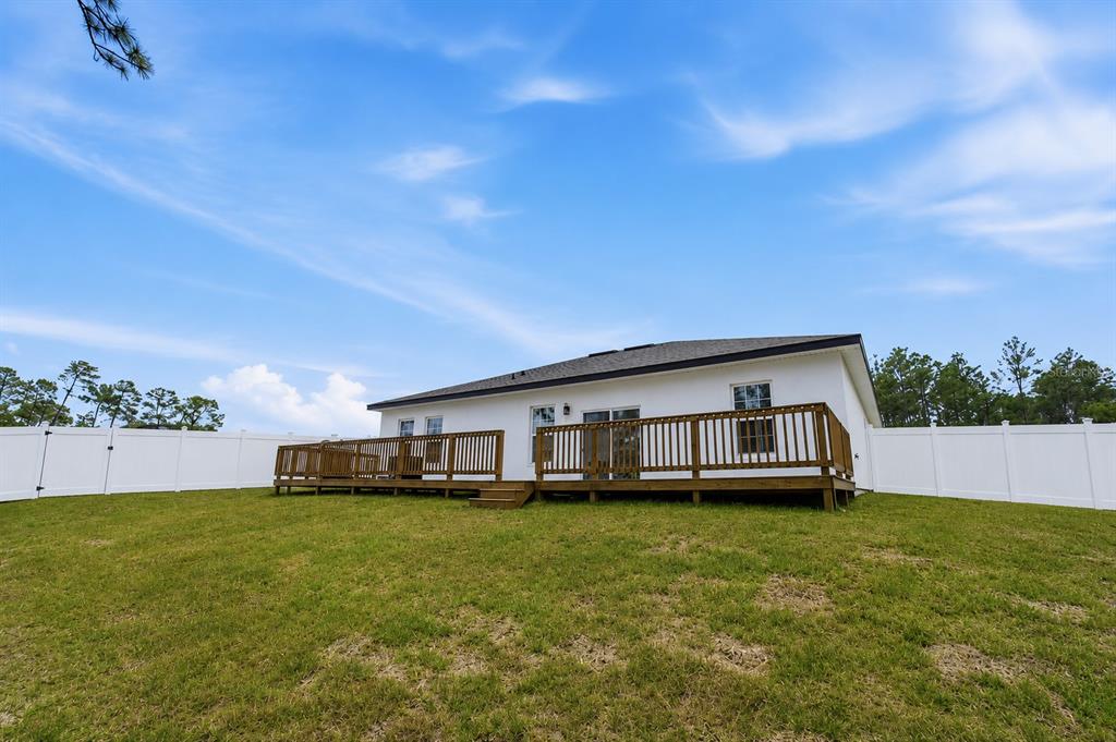 The backyard of a white house features a wooden deck and a white vinyl fence — 785 MARION OAKS TRL UNIT 785, OCALA, FL