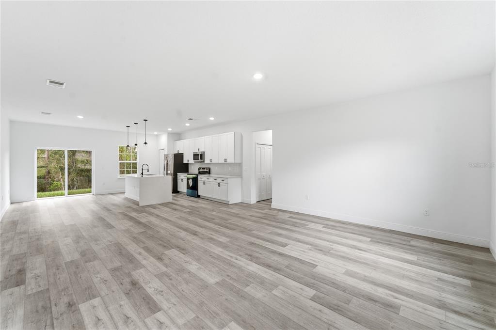 An open-concept kitchen and living area features white cabinetry, a kitchen island, and wood-look flooring — 785 MARION OAKS TRL UNIT 785, OCALA, FL