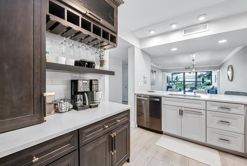 A kitchen features dark wood cabinetry, white countertops, a coffee station, and a stainless dishwasher — 3710 Whitehall Drive # 105, West Palm Beach FL 33401, WEST PALM BEACH, FL