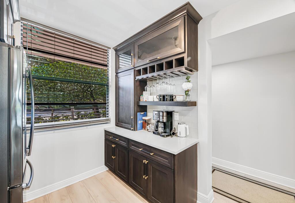 A coffee bar area features dark wood cabinetry, a white countertop, and a window with blinds — 3710 Whitehall Drive # 105, West Palm Beach FL 33401, WEST PALM BEACH, FL