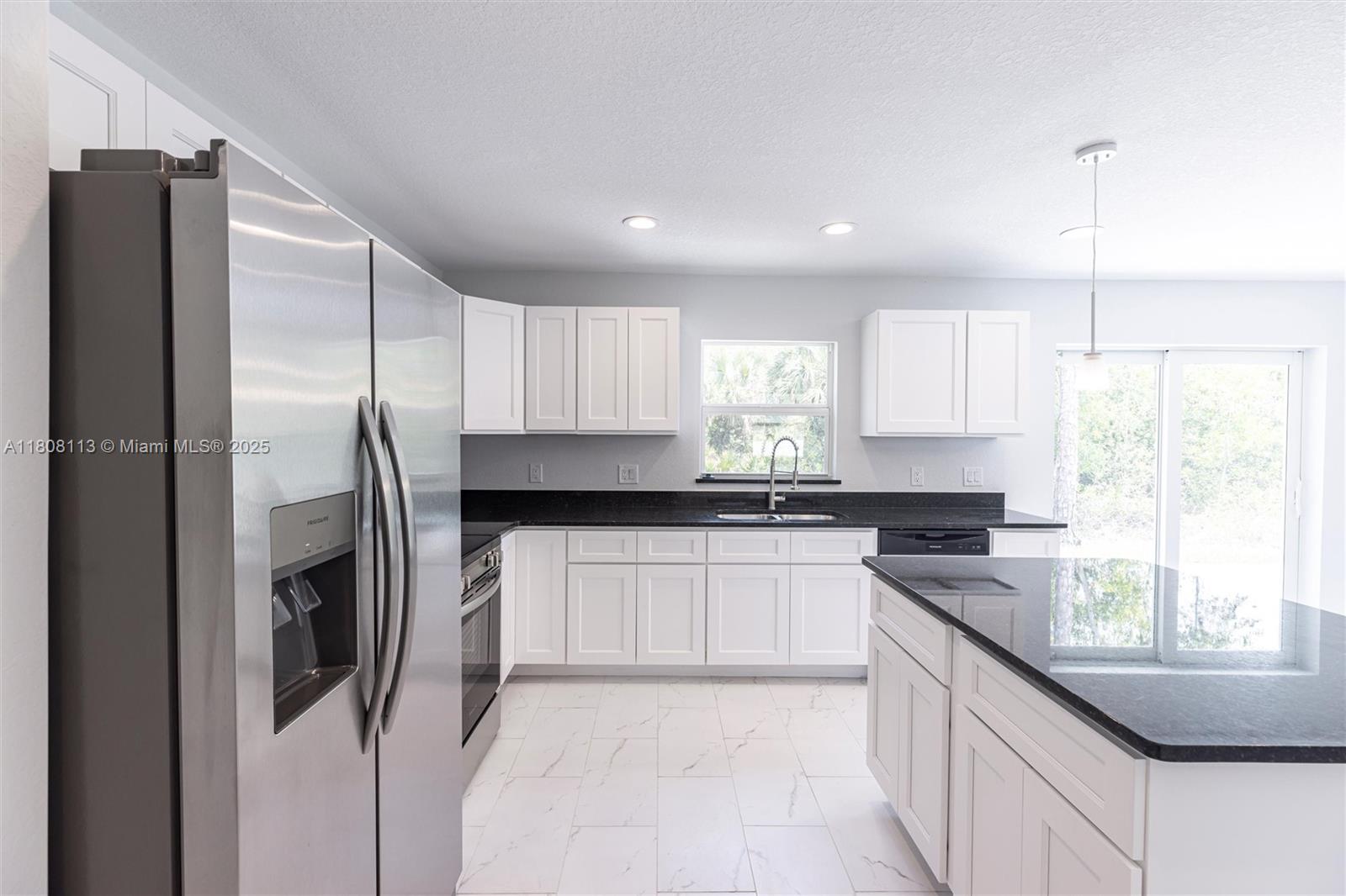 A kitchen features white cabinets, black countertops, stainless steel appliances, and light-colored tile flooring — 2006 Rosa Ct # 2006, Lehigh Acres FL 33972, LEHIGH ACRES, FL