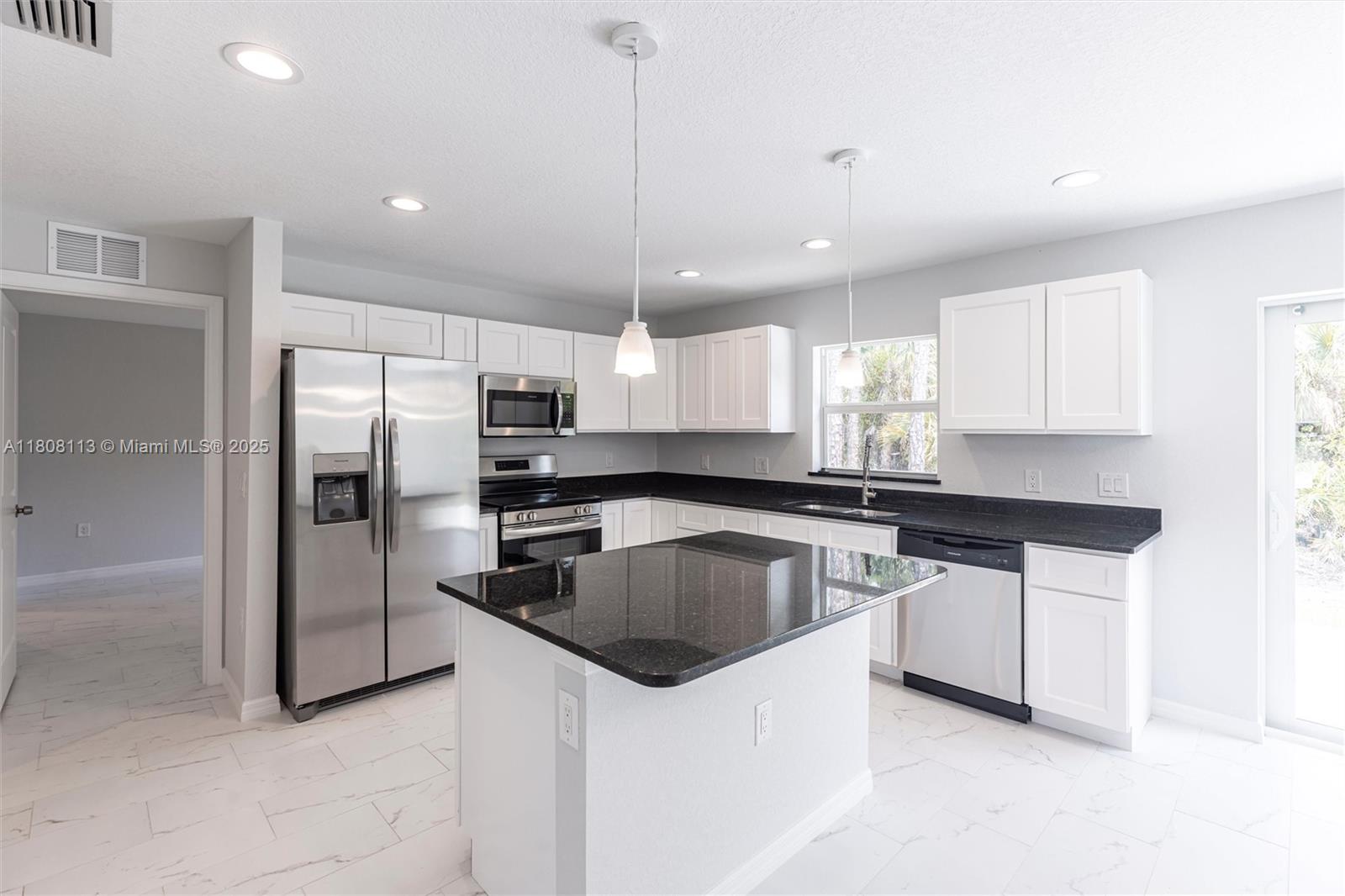A kitchen features white cabinets, black countertops, stainless steel appliances, and a central island — 2006 Rosa Ct # 2006, Lehigh Acres FL 33972, LEHIGH ACRES, FL