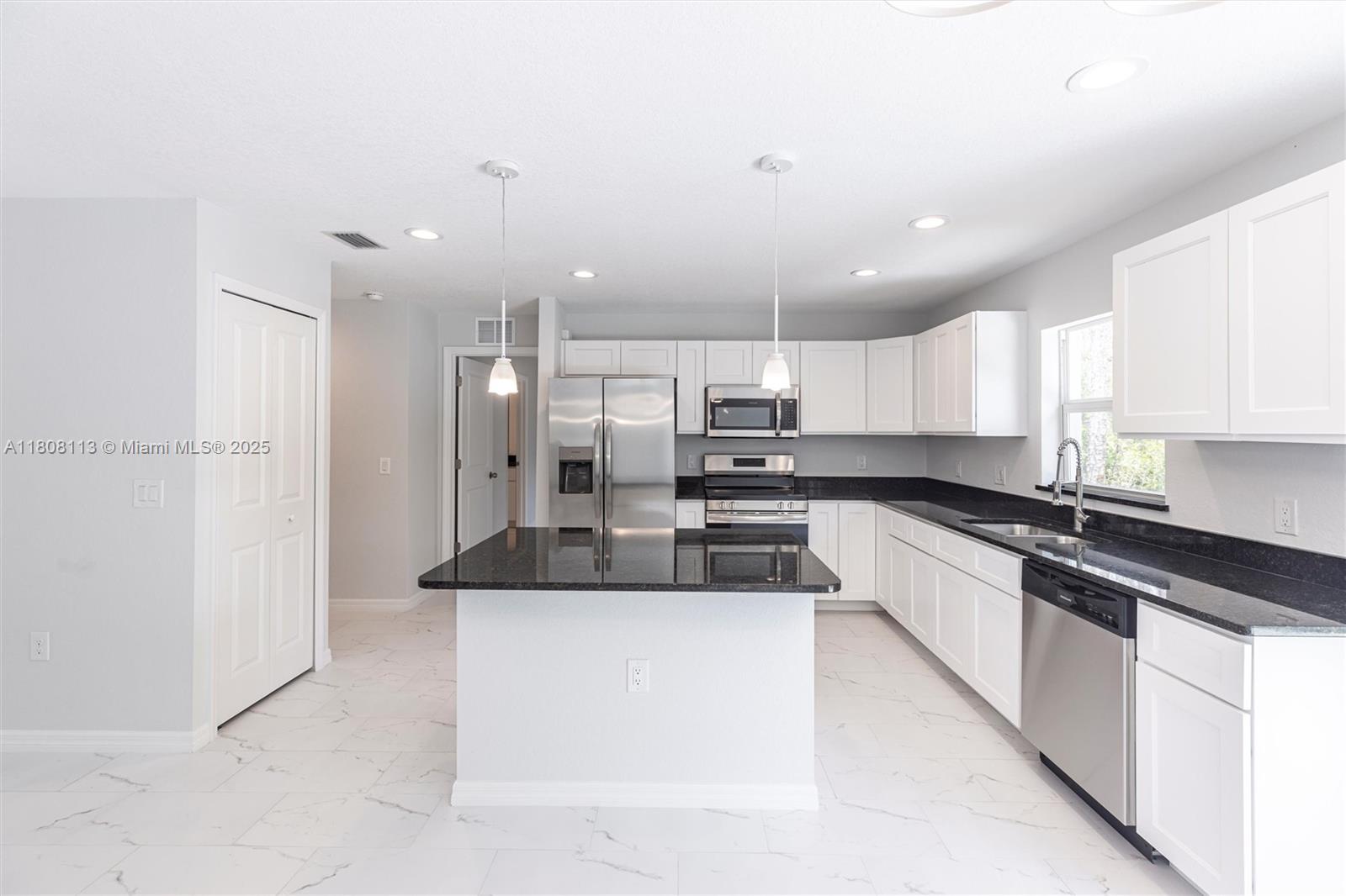 A kitchen features white cabinets, black granite countertops, a central island, and white tile flooring — 2006 Rosa Ct # 2006, Lehigh Acres FL 33972, LEHIGH ACRES, FL