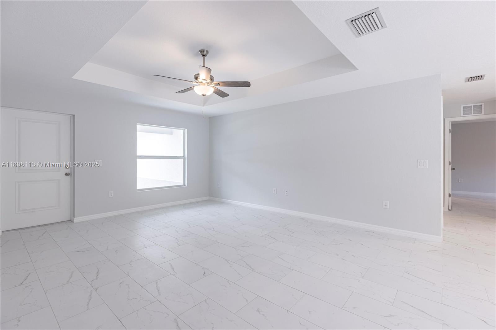 An empty room features light gray walls, white marble-look tile flooring, and a tray ceiling — 2006 Rosa Ct # 2006, Lehigh Acres FL 33972, LEHIGH ACRES, FL