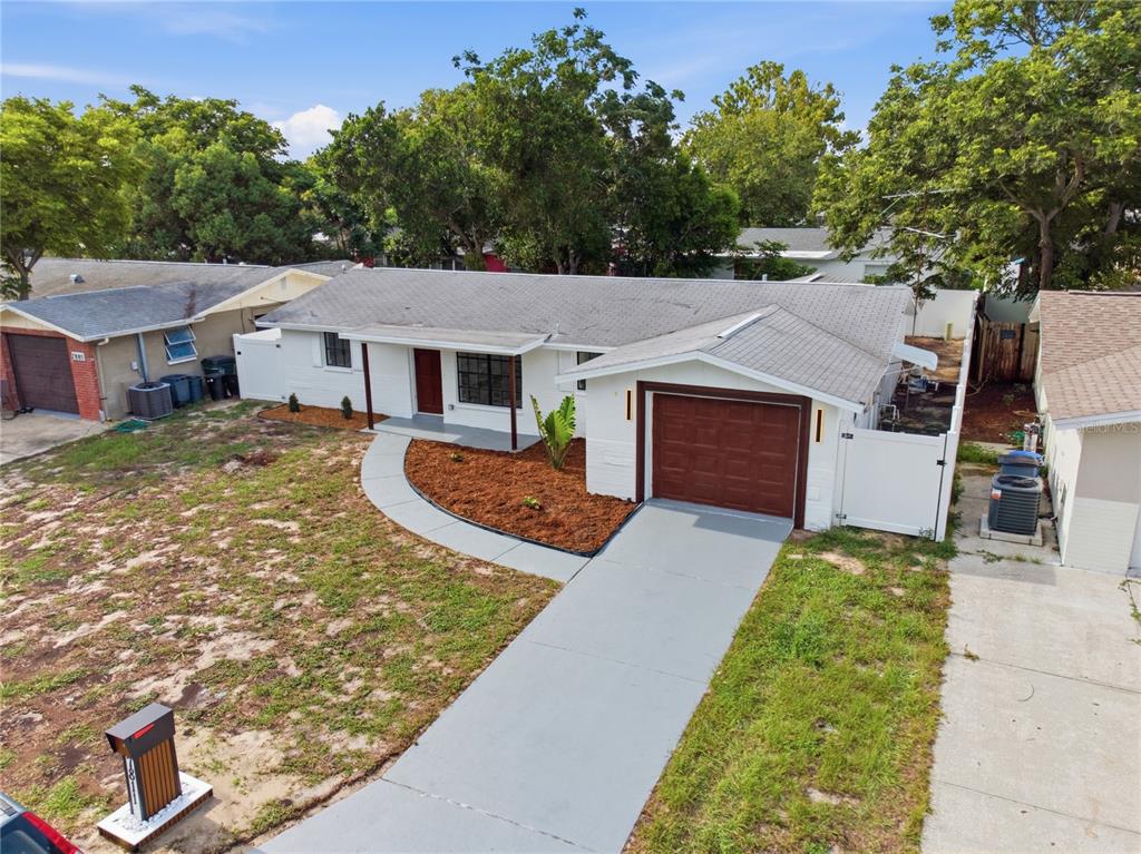 An aerial view of a single-story white house with a brown garage and front door — 7811 TYSON DRIVE, PORT RICHEY, FL