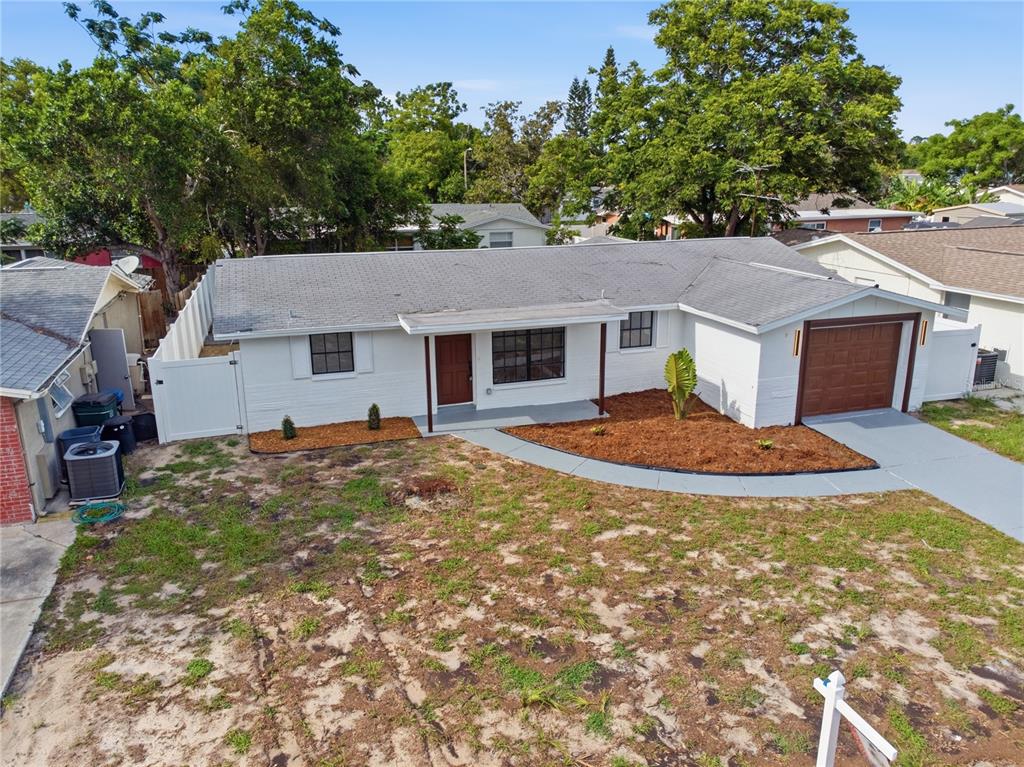 An aerial view of a single-story white house with a brown garage and front door — 7811 TYSON DRIVE, PORT RICHEY, FL