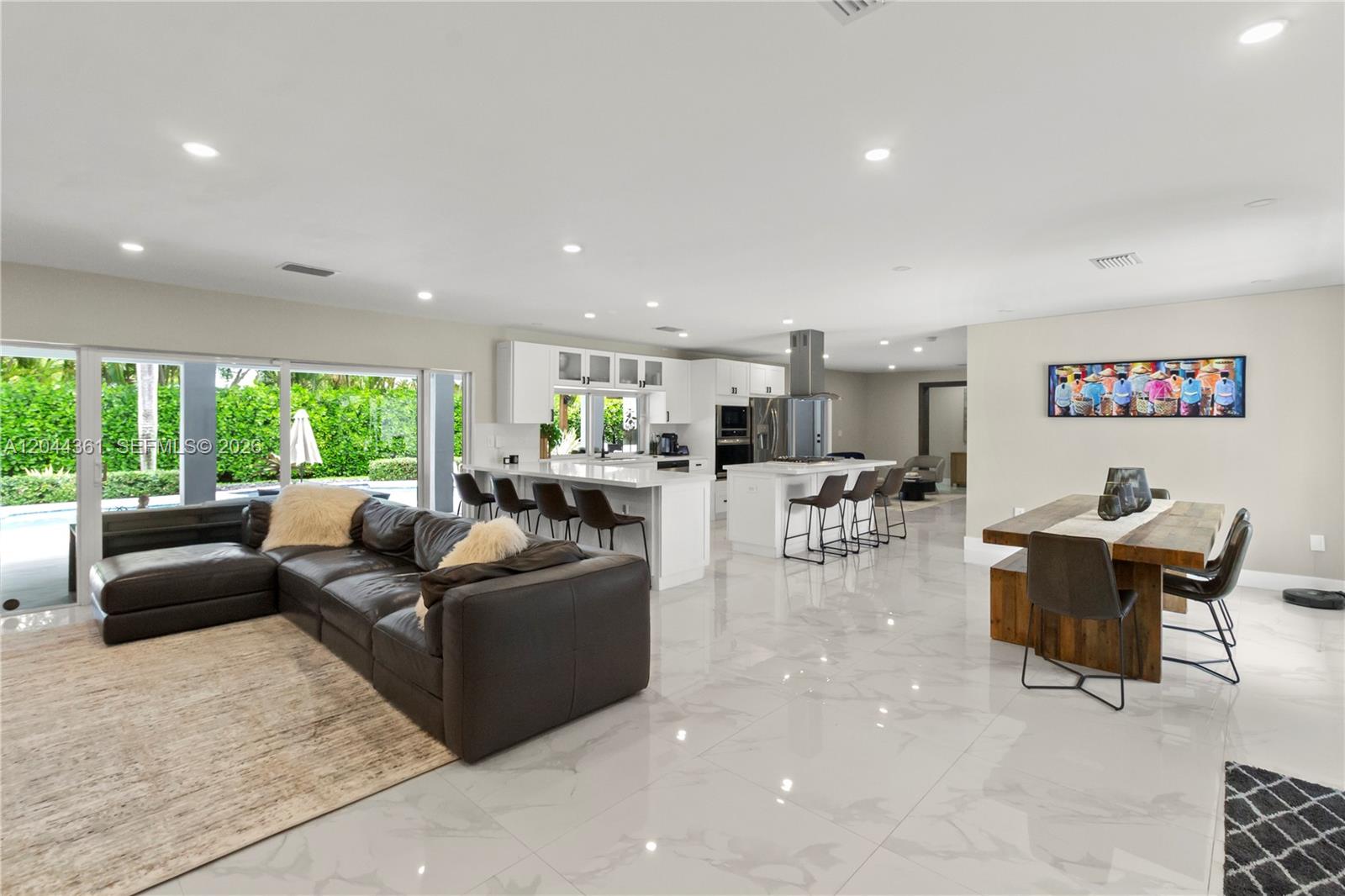 A modern kitchen features white cabinetry, stainless steel appliances, a center island, and marble flooring — 12900 SW 112th Ave, Miami FL 33176, MIAMI, FL