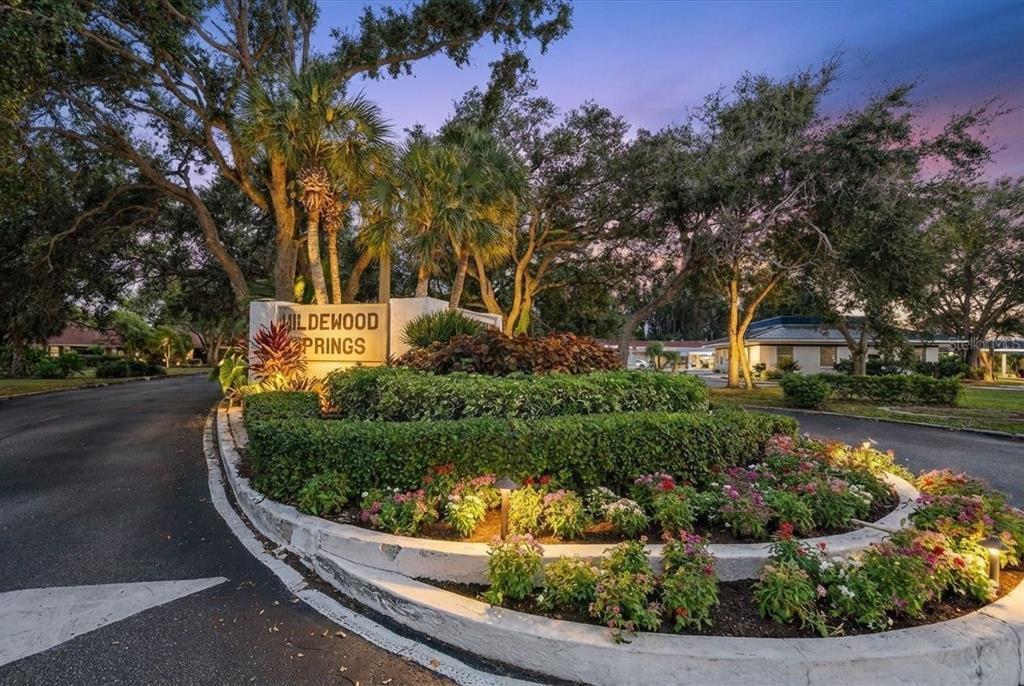 The entrance sign for Wildewood Springs is surrounded by landscaped gardens and mature trees — 257 SHERWOOD DRIVE UNIT 257, BRADENTON, FL