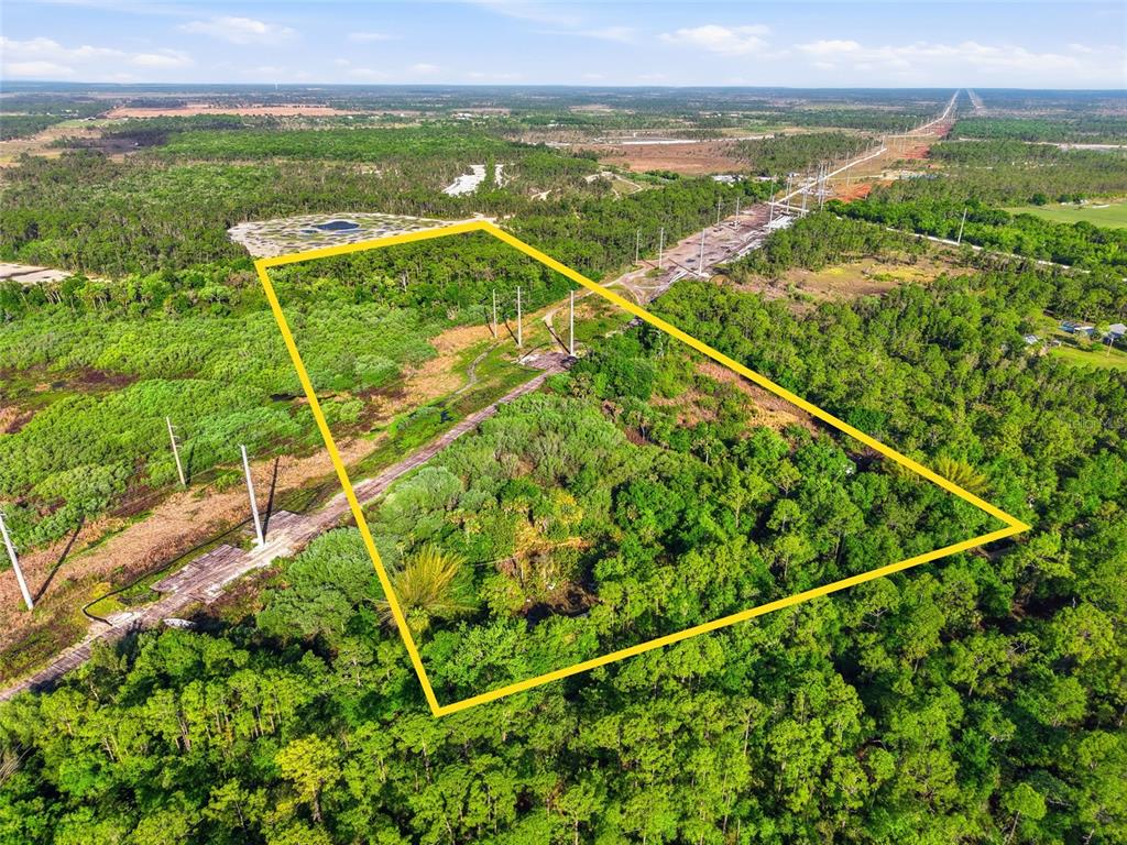 An aerial view shows a rectangular plot of undeveloped, wooded land outlined in yellow — 22811 WILLIAMS DRIVE, NORTH FORT MYERS, FL