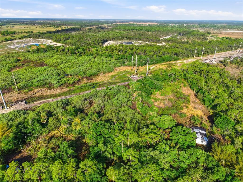 An aerial view shows a wooded lot with a small structure and utility poles — 22811 WILLIAMS DRIVE, NORTH FORT MYERS, FL