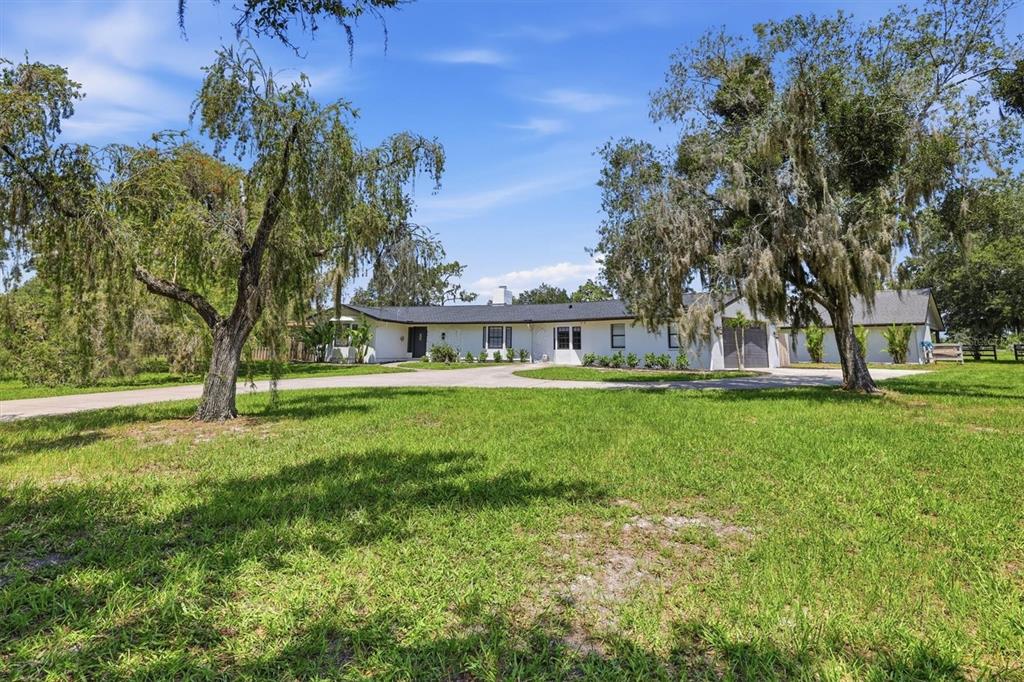 A single-story white house with a dark roof sits behind a large grassy lawn — 3810 HIDDEN RIVER ROAD, SARASOTA, FL