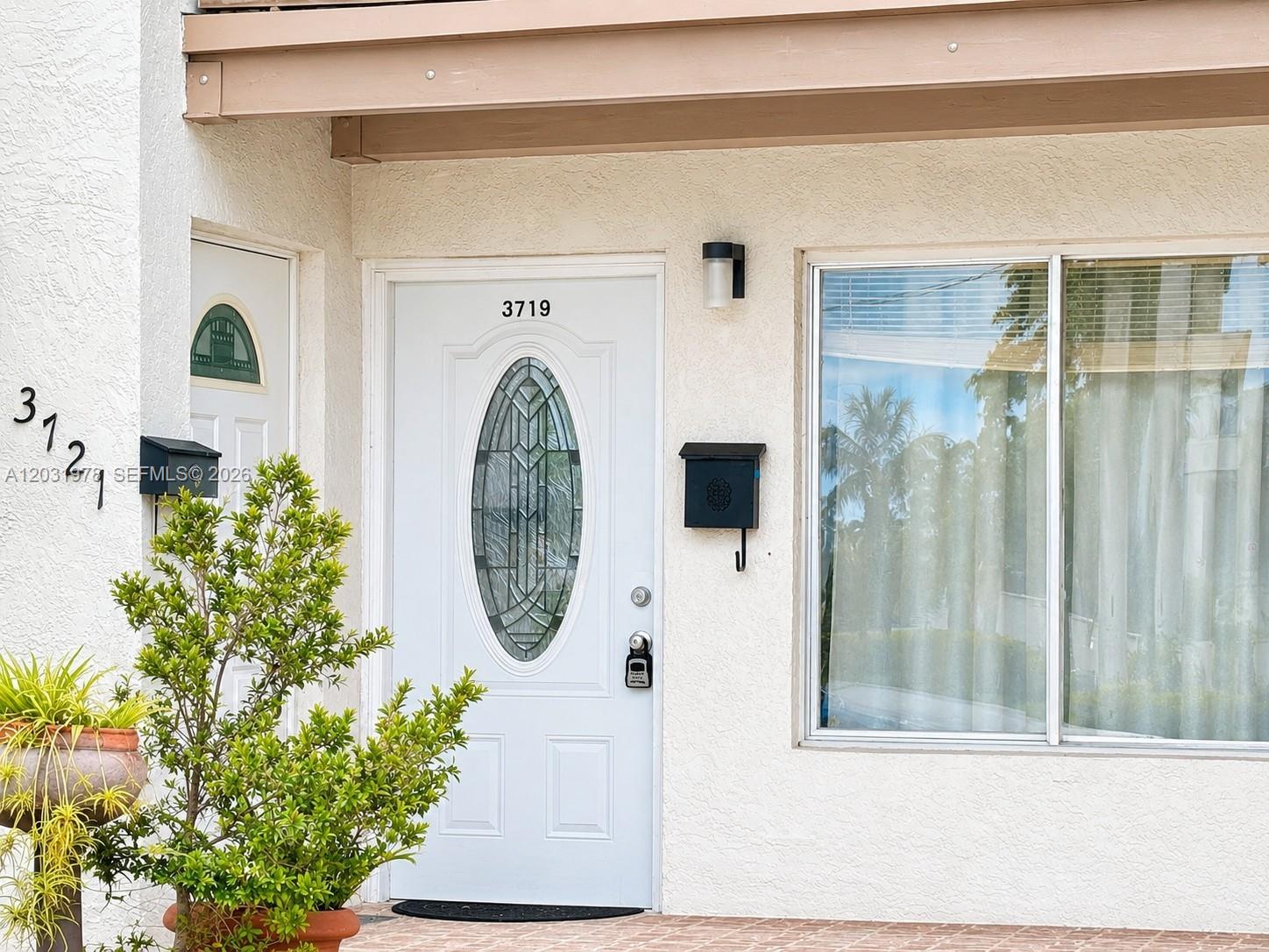 A white front door with an oval glass insert sits beside a large window — 3719 Riverside Dr, Coral Springs FL 33065, CORAL SPRINGS, FL