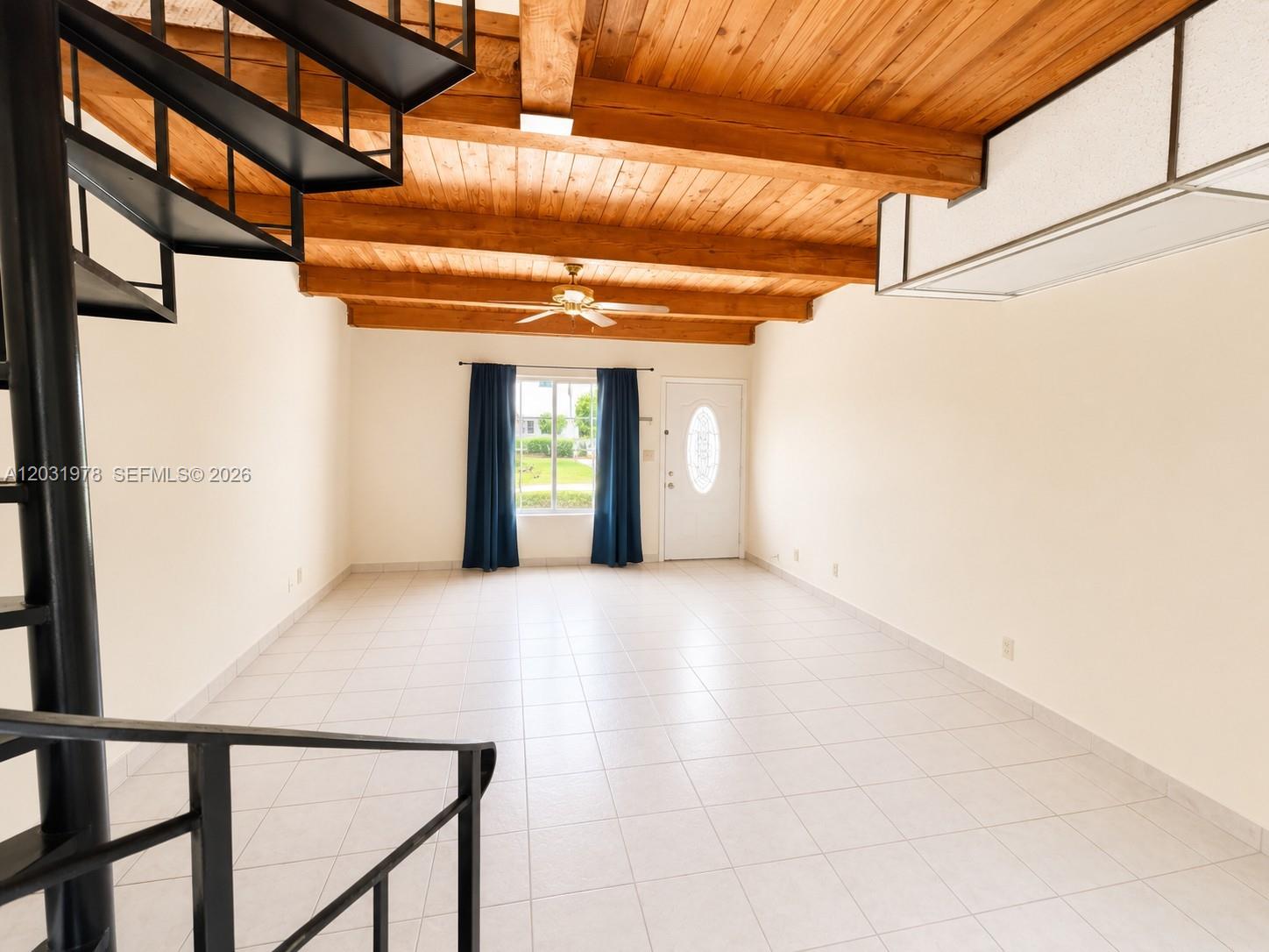 A living room features a spiral staircase, tile flooring, and a wood-beamed ceiling — 3719 Riverside Dr, Coral Springs FL 33065, CORAL SPRINGS, FL