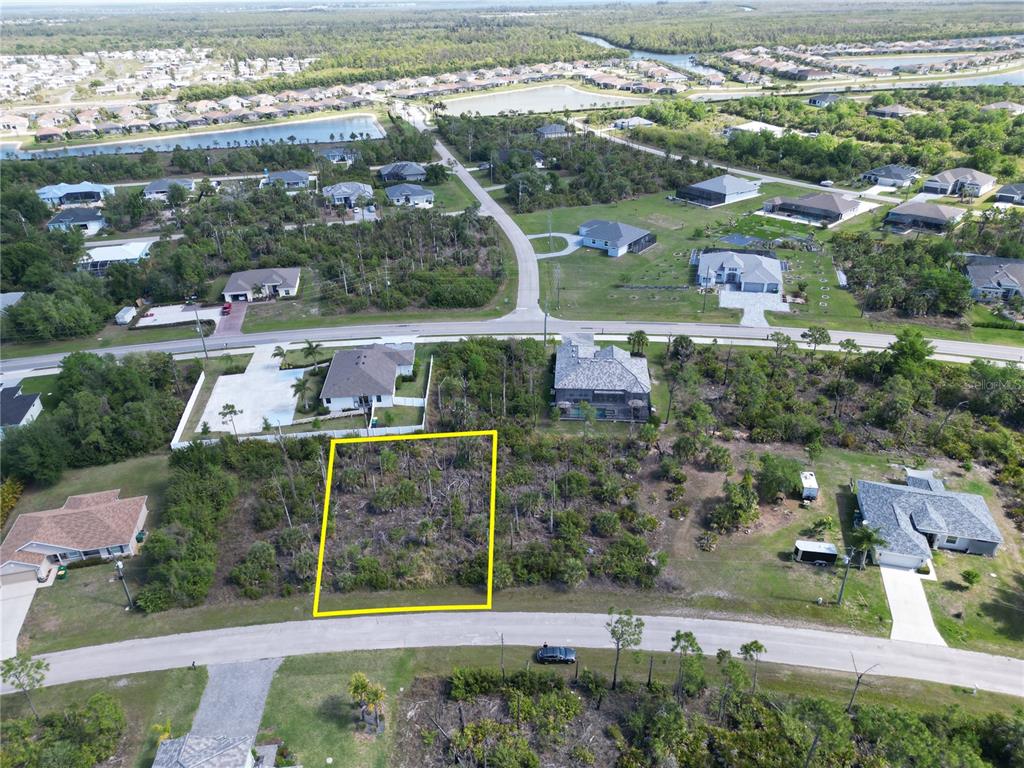 An aerial view shows a vacant, rectangular residential lot outlined in yellow along a paved road — 14390 DAFOE STREET, PORT CHARLOTTE, FL