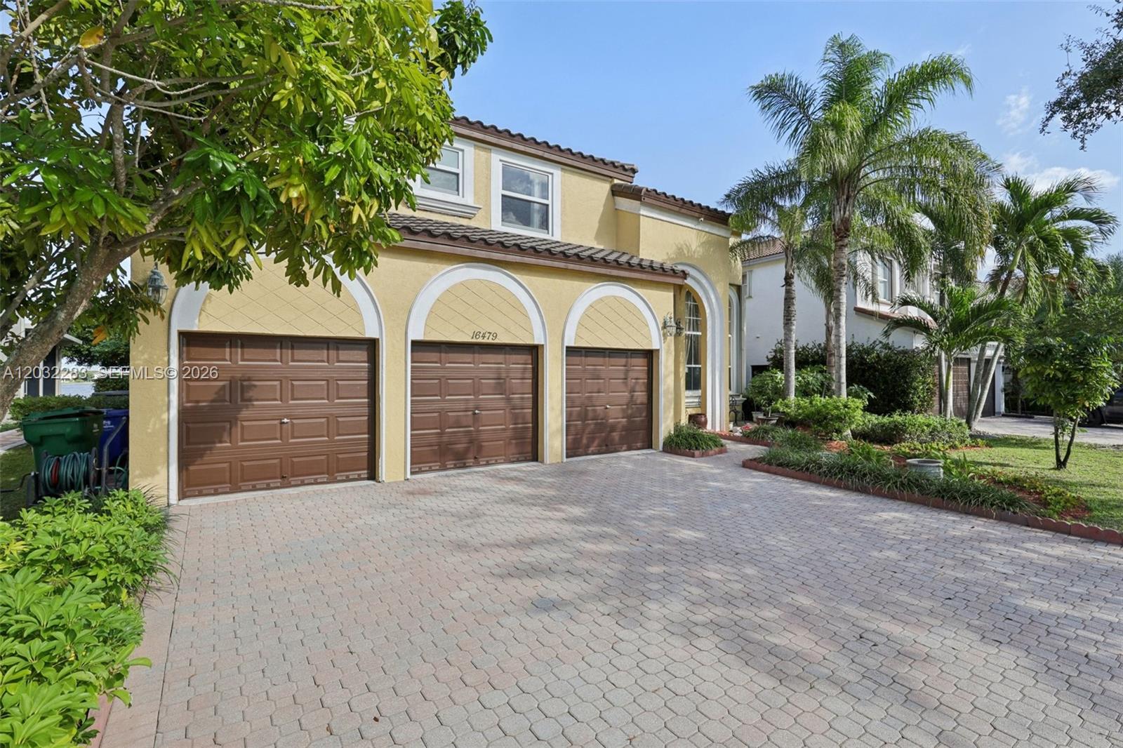 A yellow two-story house features a three-car garage and a paved driveway — 16479 SW 54th Ct, Miramar FL 33027, MIRAMAR, FL