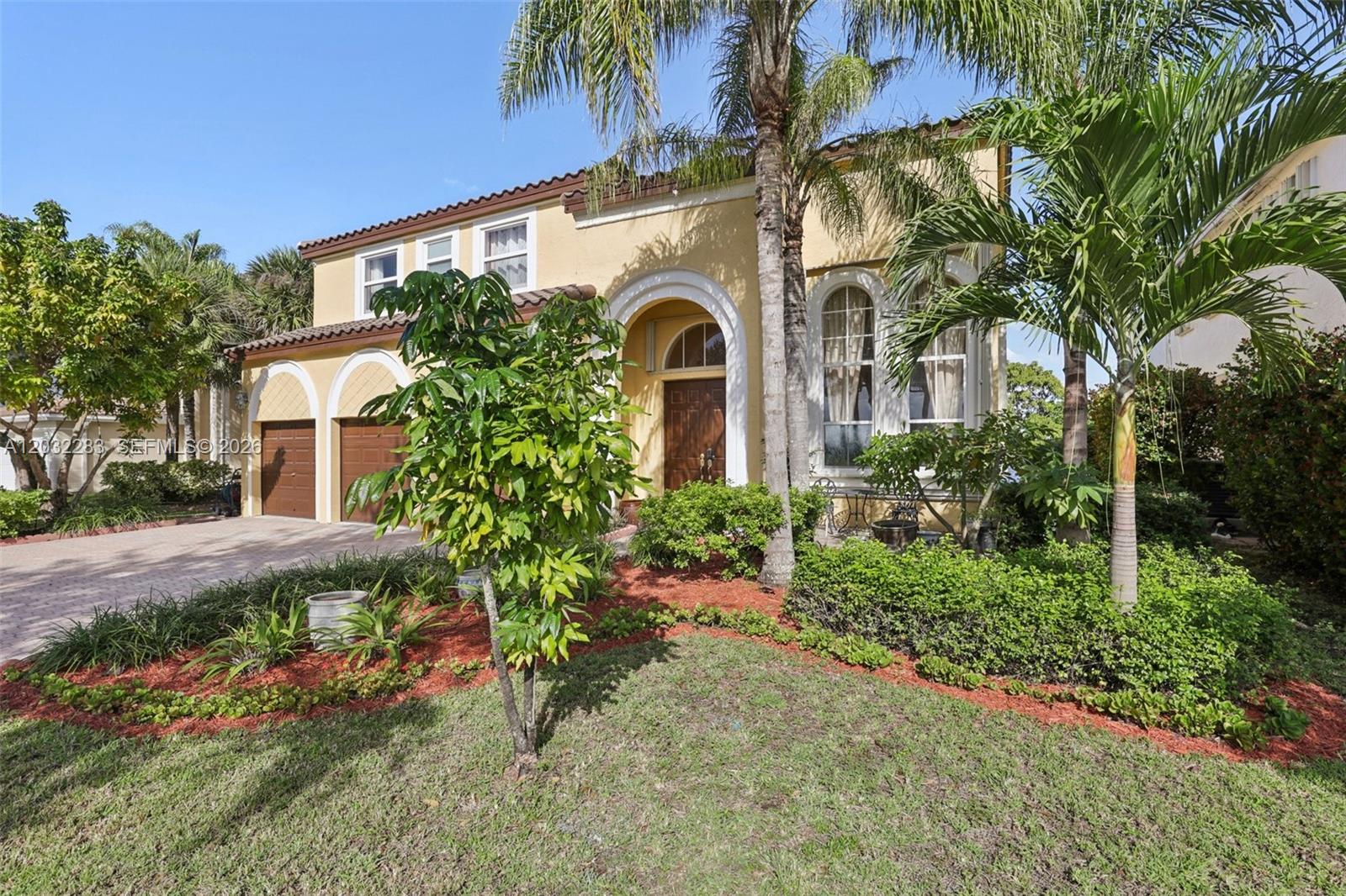 A two-story yellow house with a two-car garage, arched entryway, and palm trees — 16479 SW 54th Ct, Miramar FL 33027, MIRAMAR, FL