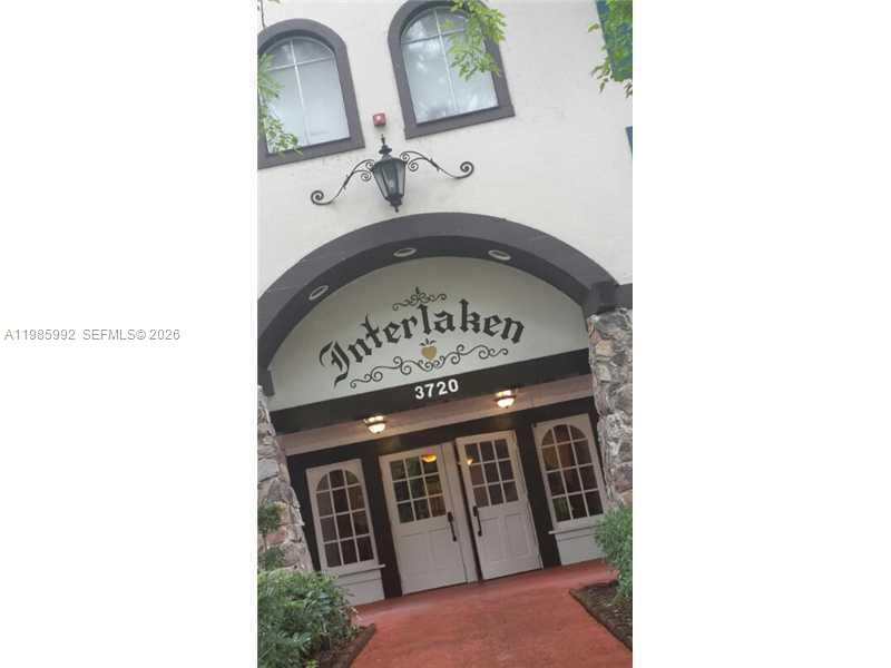 The exterior entrance of a building features an arched doorway with the name Interlaken displayed — 3720 INVERRARY DR # 2M, Lauderhill FL 33319, LAUDERHILL, FL