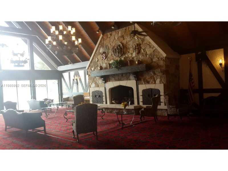 A large, rustic living room features a stone fireplace, vaulted wood ceilings, and red carpeting — 3720 INVERRARY DR # 2M, Lauderhill FL 33319, LAUDERHILL, FL