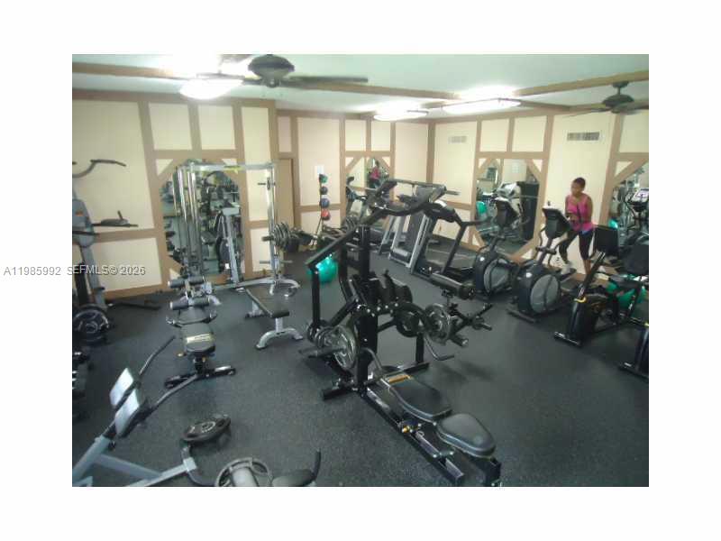 A gym room features various exercise machines, mirrors, and a dark rubber floor — 3720 INVERRARY DR # 2M, Lauderhill FL 33319, LAUDERHILL, FL