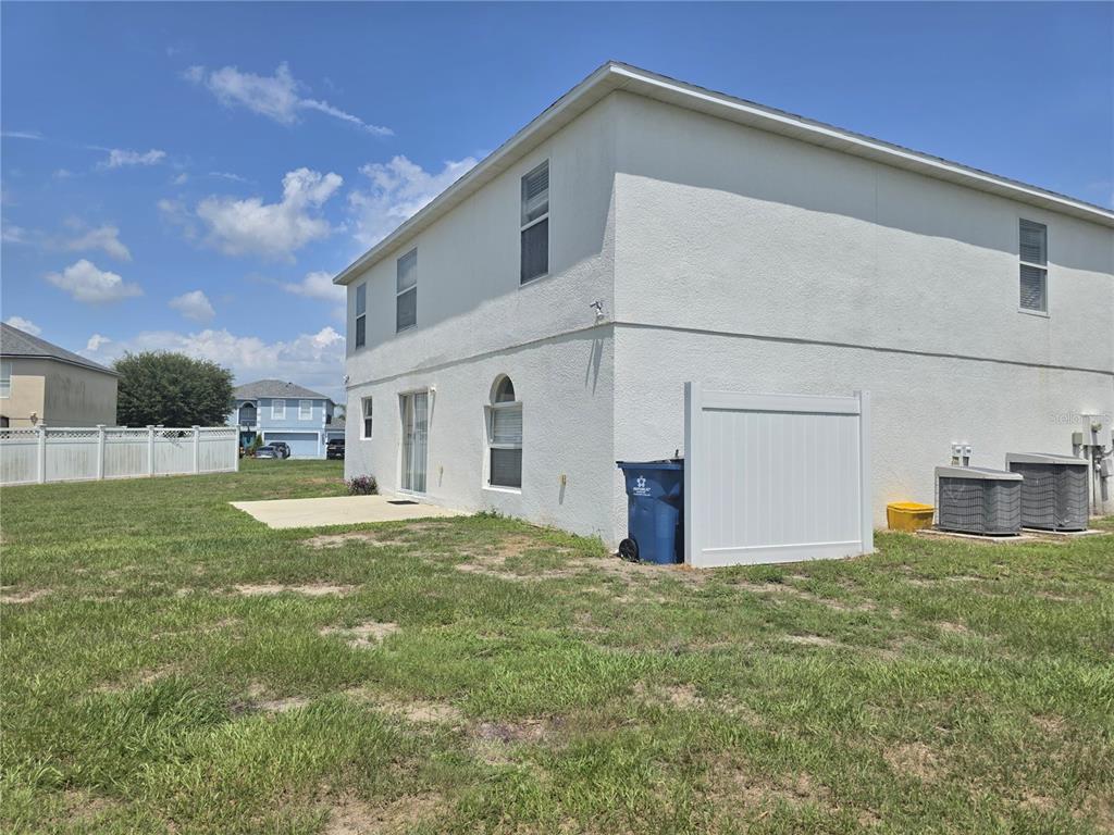 The exterior of a two-story house features a concrete patio, white vinyl fencing, and HVAC units — 145 VISTA VIEW AVENUE, EAGLE LAKE, FL