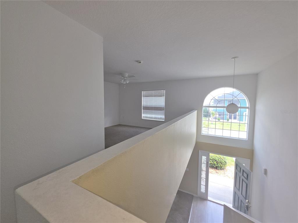 An elevated view looks down from a carpeted loft toward an open front entryway — 145 VISTA VIEW AVENUE, EAGLE LAKE, FL