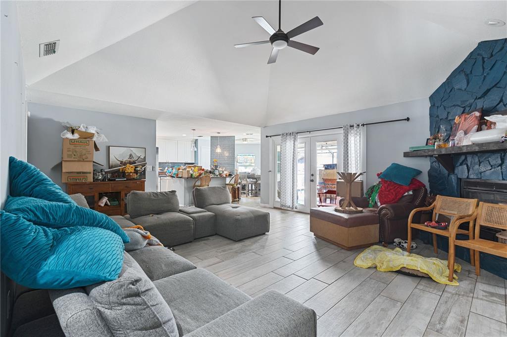 A living room features a vaulted ceiling, a blue stone fireplace, and light wood-look flooring — 6645 FREEPORT DRIVE, SPRING HILL, FL