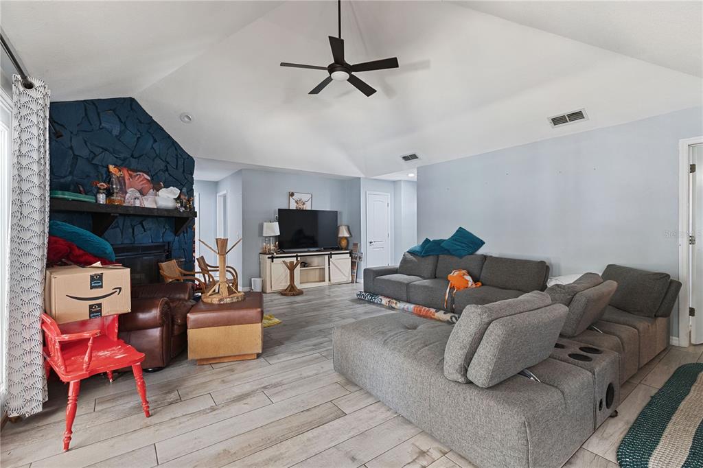 A living room features a vaulted ceiling, a blue stone fireplace, and gray sectional seating — 6645 FREEPORT DRIVE, SPRING HILL, FL
