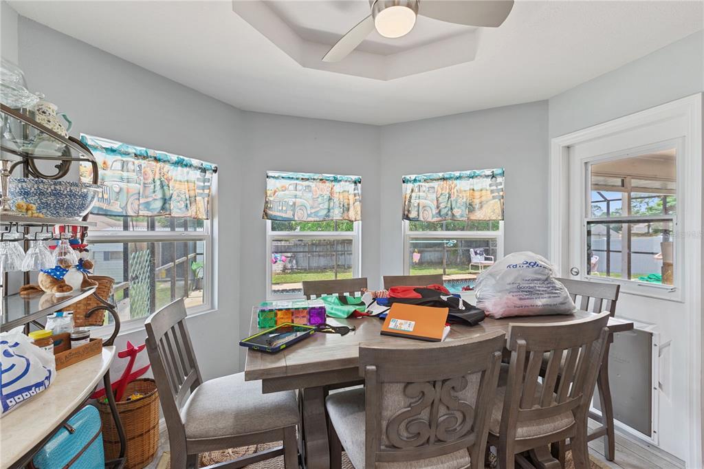 A dining area features a wooden table, chairs, light gray walls, and windows with valances — 6645 FREEPORT DRIVE, SPRING HILL, FL