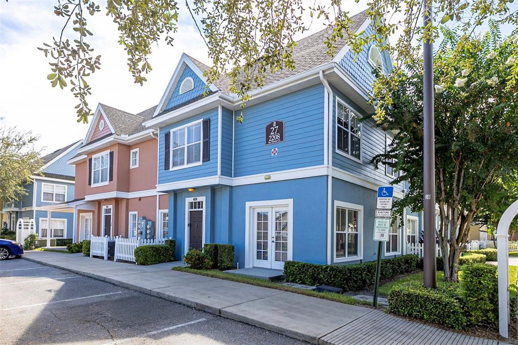 A blue two-story townhouse with a white-trimmed entrance and a handicap parking sign — 2208 SAN VITTORINO CIRCLE UNIT 107, KISSIMMEE, FL