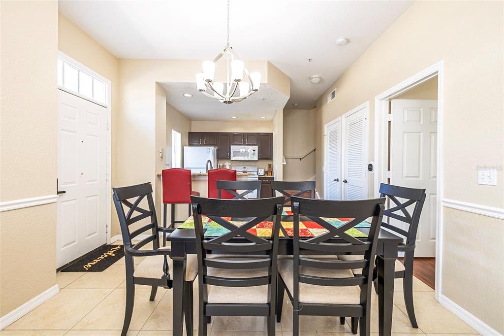 A dining area with a dark table and chairs sits in front of a kitchen — 2208 SAN VITTORINO CIRCLE UNIT 107, KISSIMMEE, FL