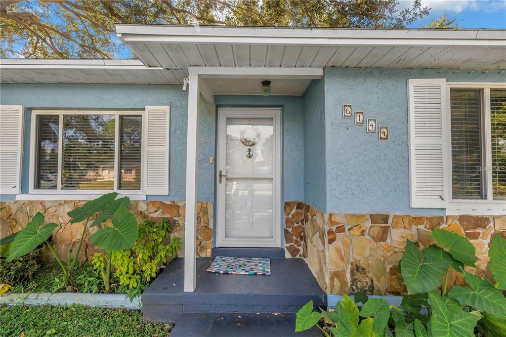 The exterior of a blue house features a stone base, white shutters, and a front door — 6144 2ND AVENUE N, ST PETERSBURG, FL
