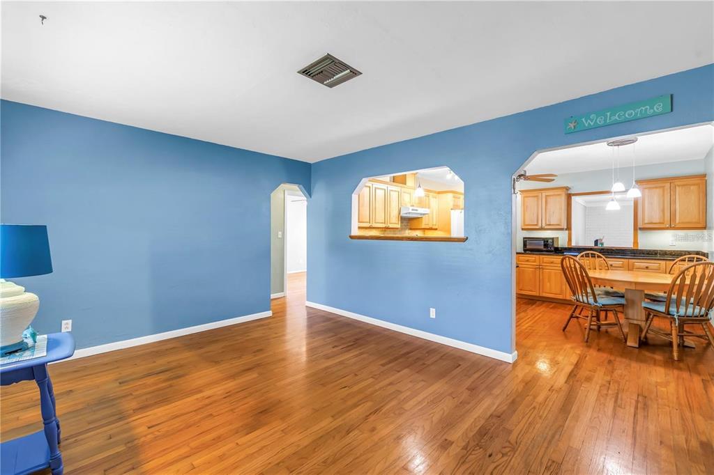 A blue-walled dining area features hardwood floors and an open pass-through into the kitchen — 6144 2ND AVENUE N, ST PETERSBURG, FL